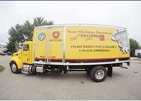 Photograph of a large, yellow shredding truck.